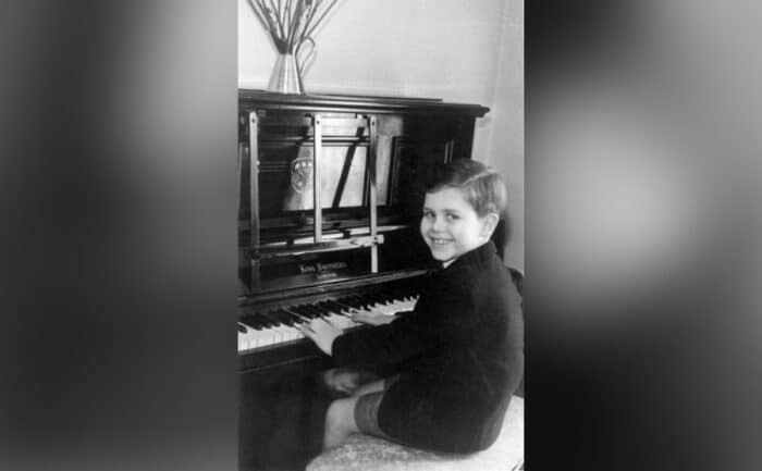 A young Elton plays at the piano at home.
