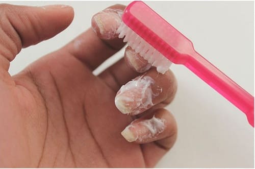 Using toothbrush to put toothpaste on nails