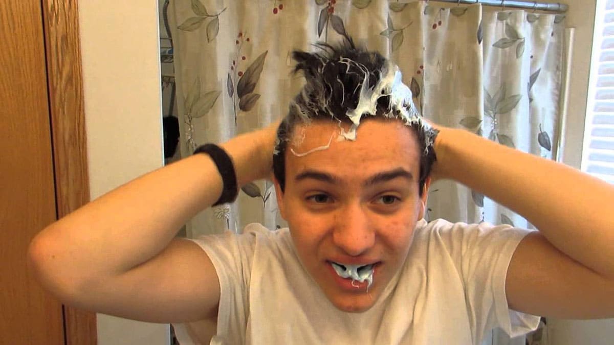 A boy putting toothpaste in his hair