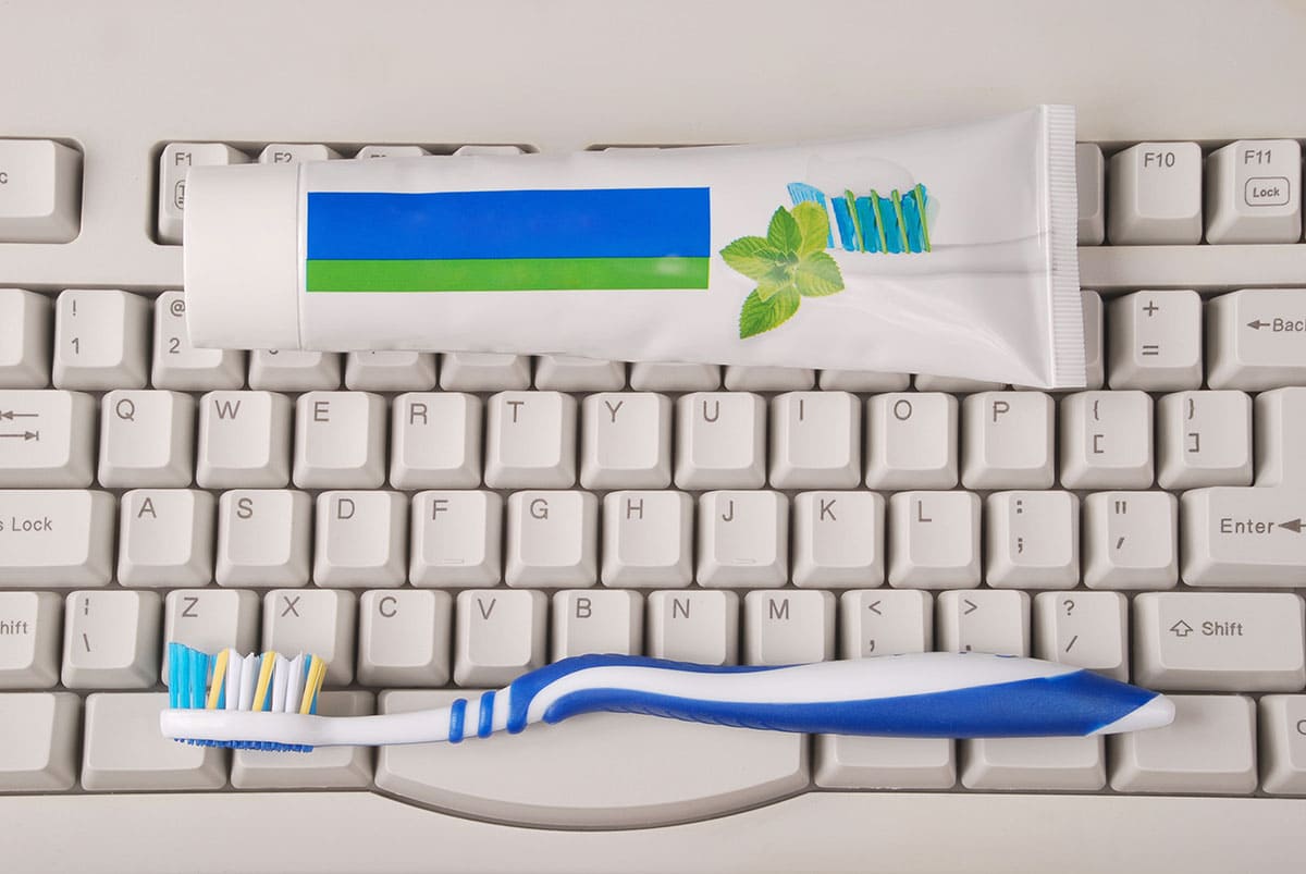 A tube of toothpaste and toothbrush on a computer keyboard