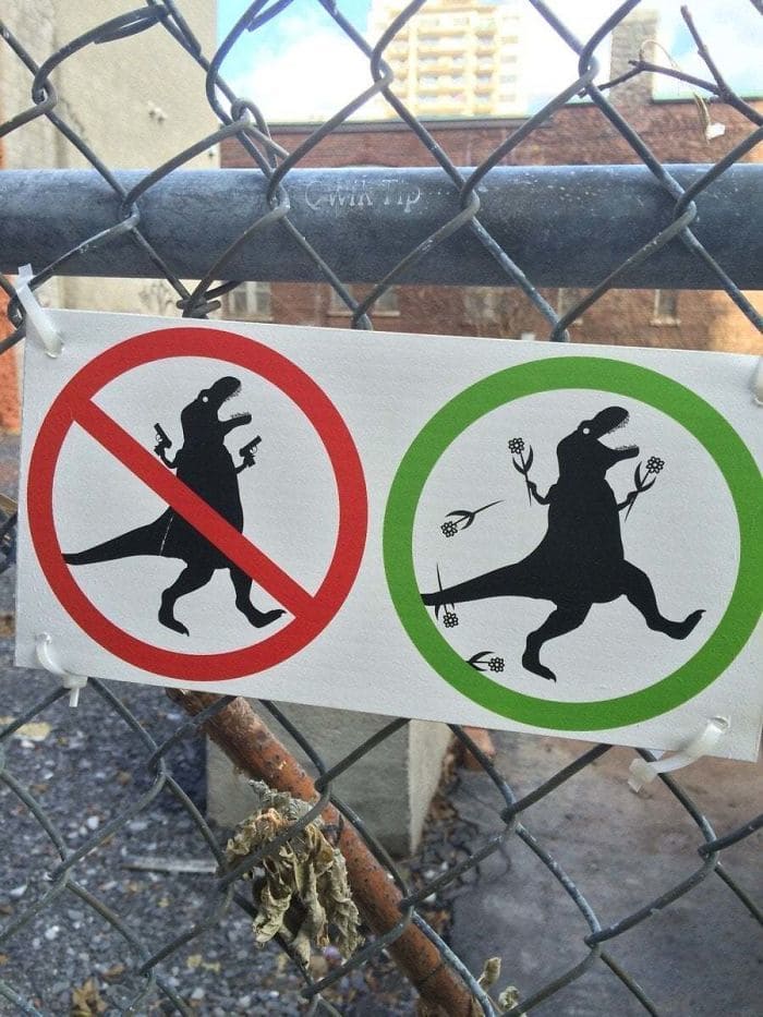 Sign on a chain-link fence with pictures of dinosaurs on it