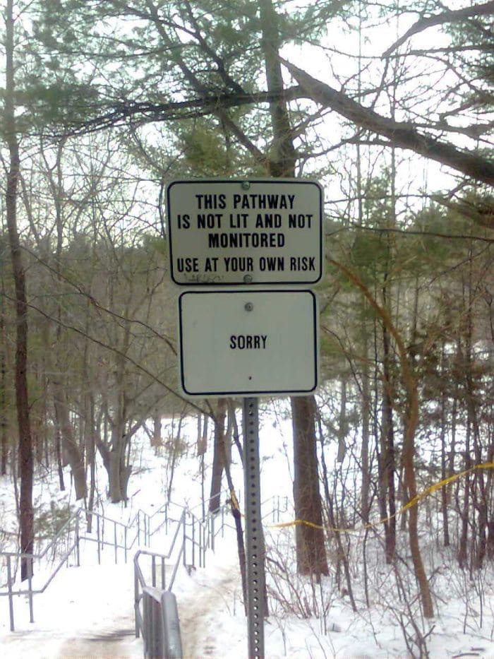 Sign in a forest about not being lit with the word “sorry” under it