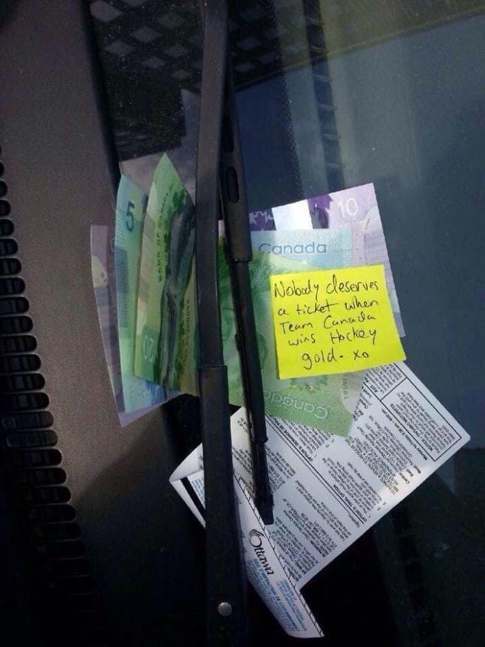 A parking ticket on a car with cash and note on it