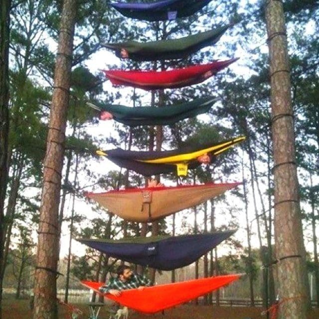 A series of hammocks set up between two trees; one on top of the other