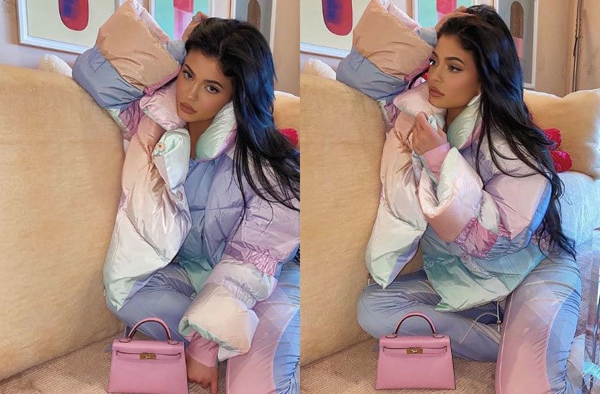 Kylie Jenner in a puffy winter coat with multiple pastel colors and matching pants with a small pink handbag. 