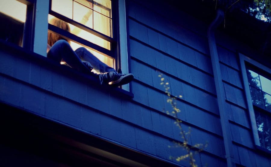 A girl sneaking out of her bedroom window 