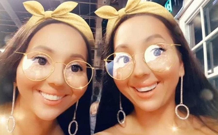Anna and Lucy with matching dangling silver earring and a filter that has a headband a gold large-rimmed glasses 