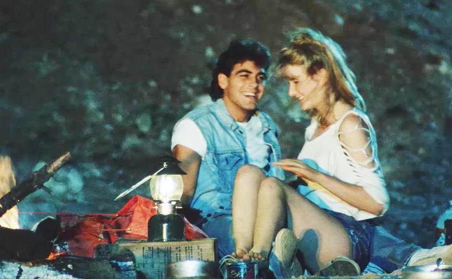 George Clooney sitting with a girl camping from the film Frizzly II: The Concert 