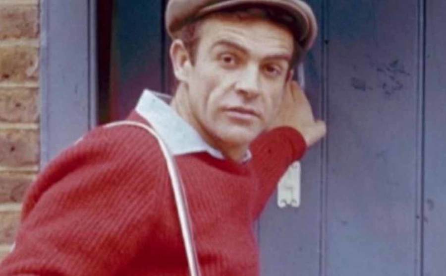 Sean Connery wearing a red sweater and brown hat in Lilacs in the Spring 