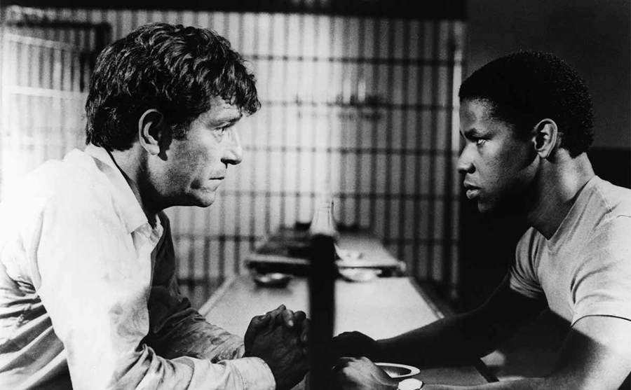 George Segal and Denzel Washington speaking to each other during a prison visit in the film Carbon Copy 