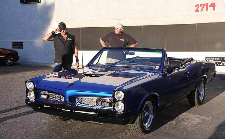 Danny Koker and Scott Smith looking at a royal blue Pontiac GTO convertible 