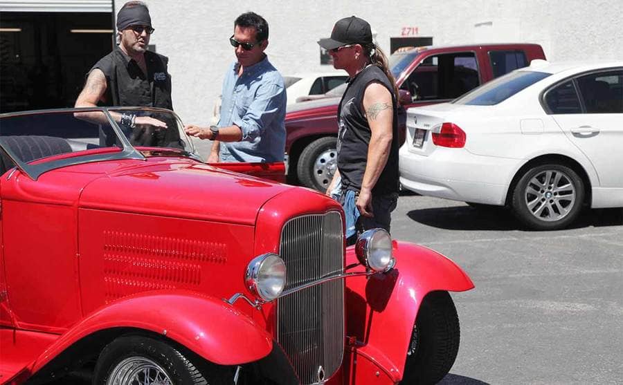 Danny Koker and Roli Szabo looking at an old red car 