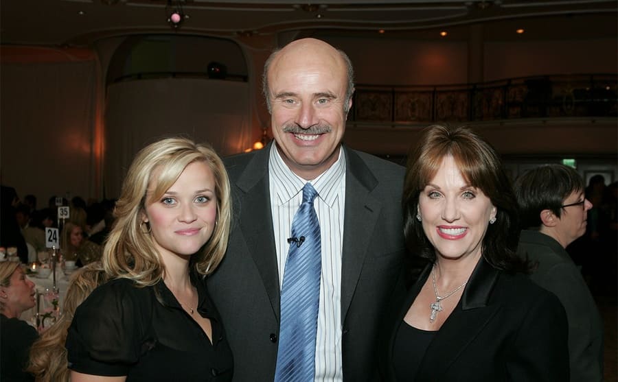 Reese Witherspoon, Dr. Phil, and Robin posing together at an awards show 