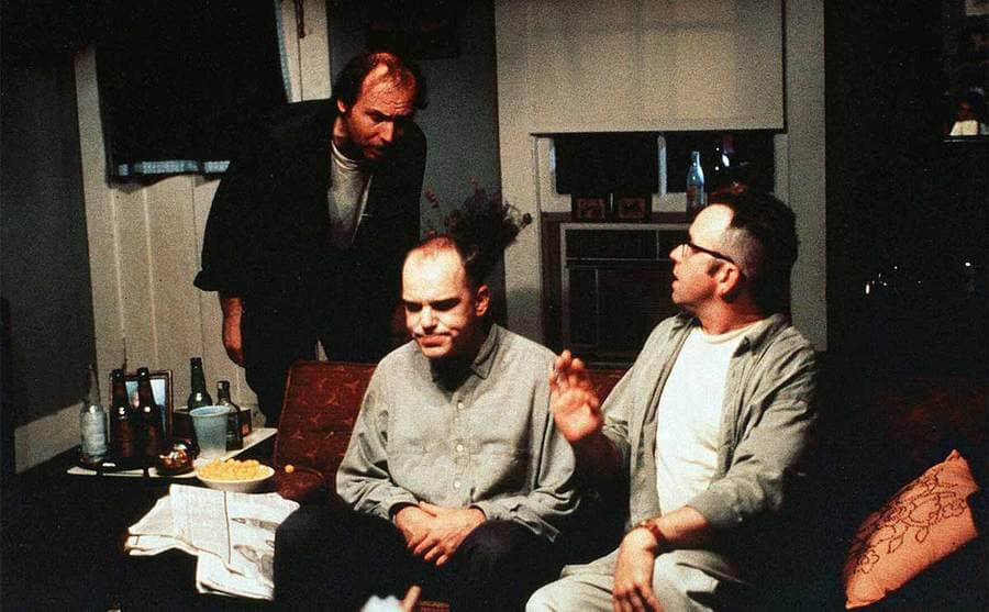 Dwight Yoakam, Billy Bob Thorton, and John Ritter having a discussion around the couch in the film Sling Blade 