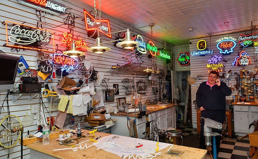 Howie Cohen talking on the phone in his neon lights shop 