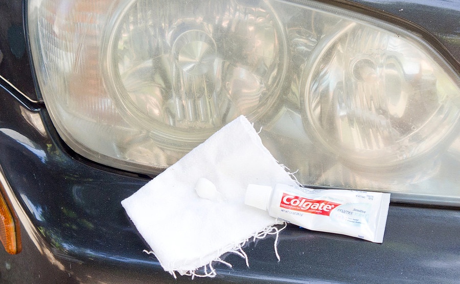 A cloth with some toothpaste on it sitting next to a foggy car headlight 