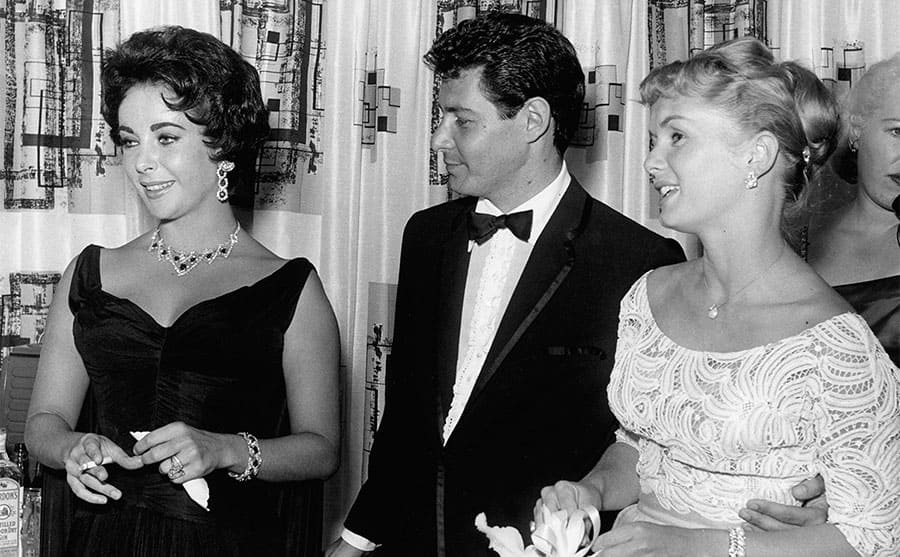 Elizabeth Taylor, Eddie Fisher, and Debbie Reynolds posing together 