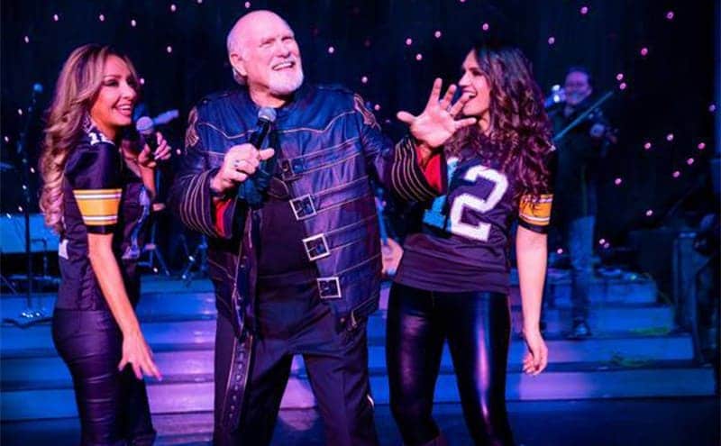 Terry Bradshaw on stage with two women in football jerseys 
