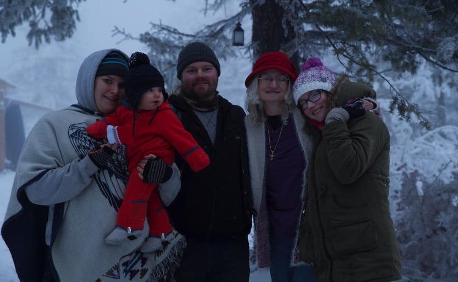 Noah, Rhain, Ami, Baby Eli, and another daughter posing in the snow covered wilderness 