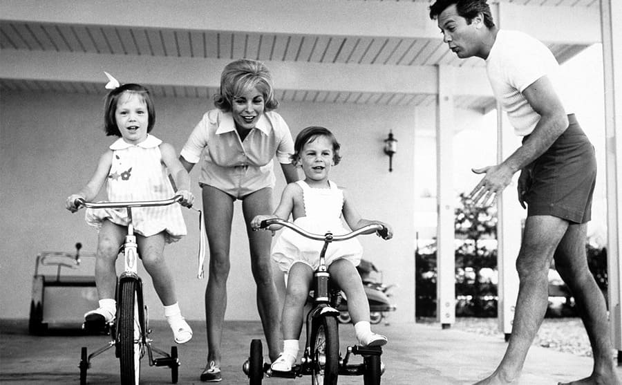 Janet Leigh and Tony Curtis with their daughters Kelly and Jamie Lee riding tricycles 
