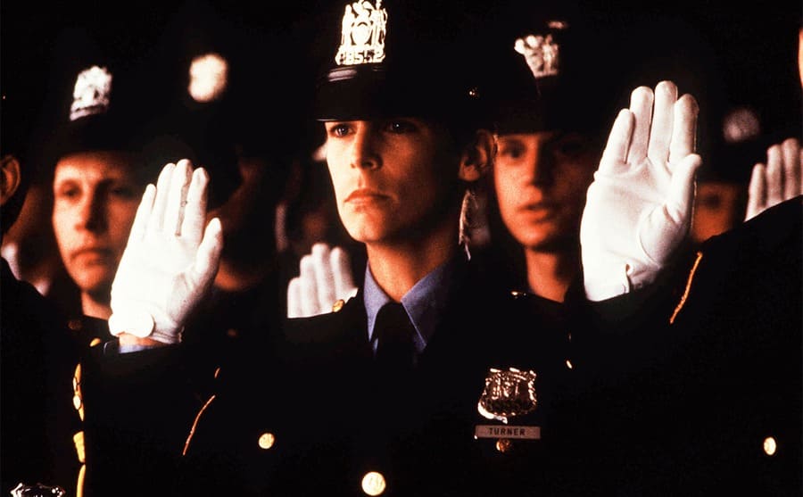Jamie Lee Curtis in a police uniform with her right hand raised