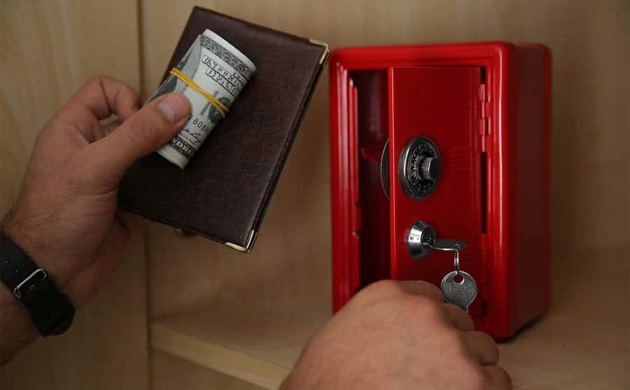 A man putting a passport and cash into a small lockbox 