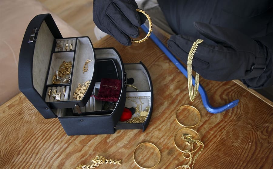 A burglar looking through a jewelry box 