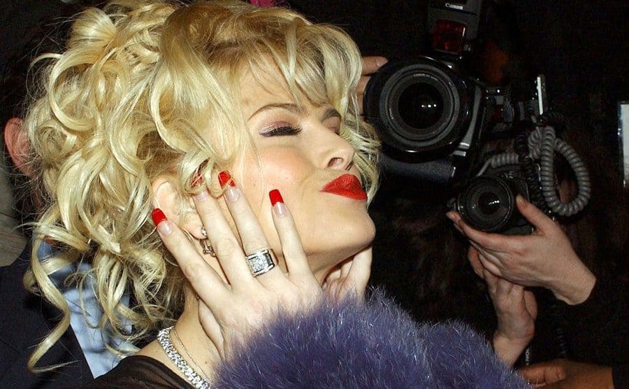 Anna Nicole Smith posing with paparazzi surroundeing her 