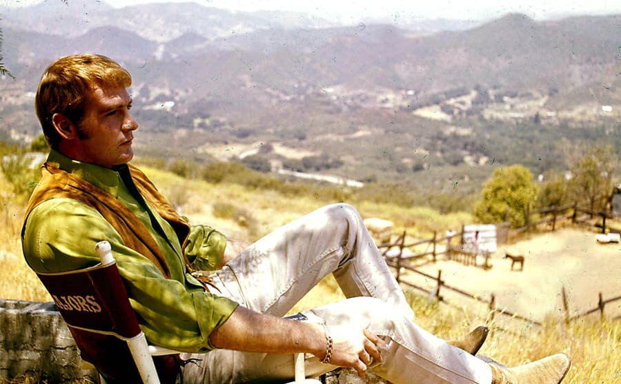 Lee r Majors sitting in a director's chair looking at the valley