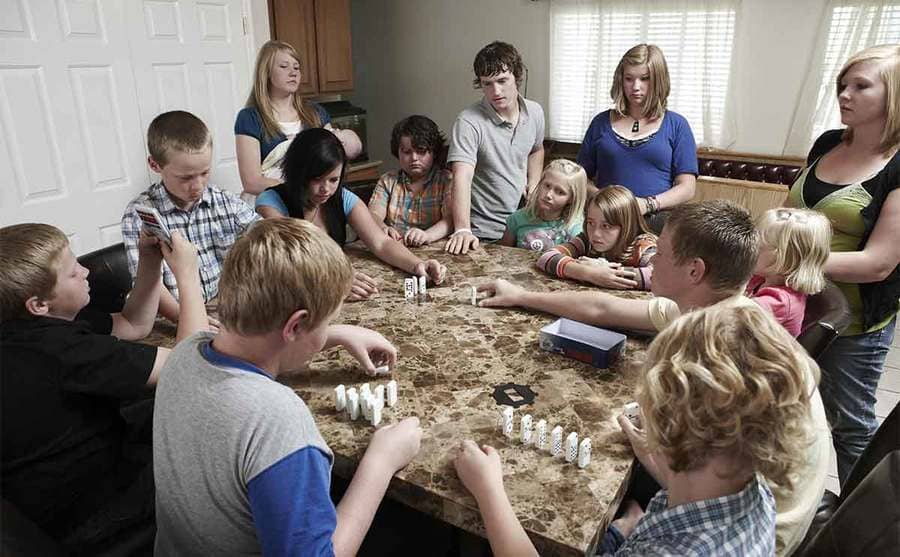 All of their kids playing dominos at the kitchen table 