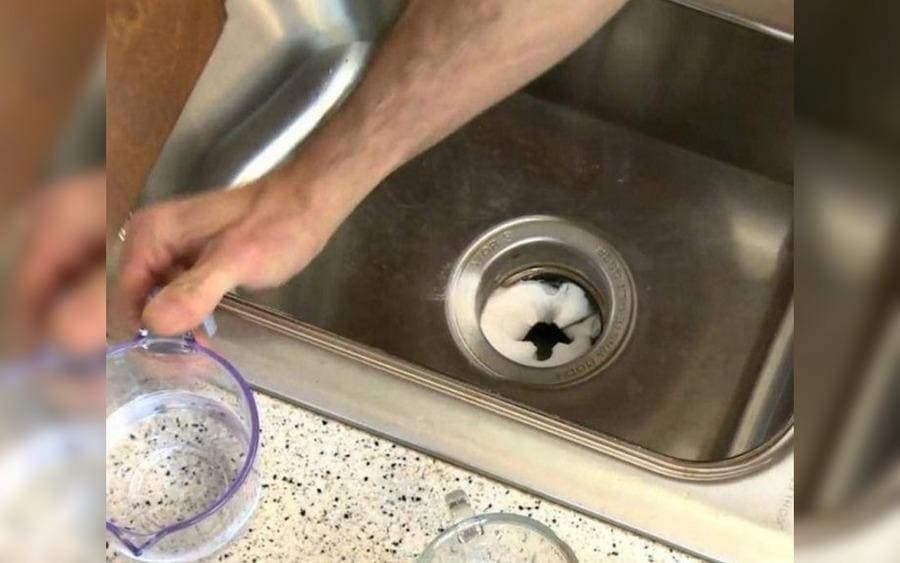  Un envase con bicarbonato de sodio es vertido sobre un embudo para limpiar un desague 