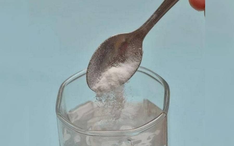  Cucharadita con bicarbonato siendo agregada a un vaso.