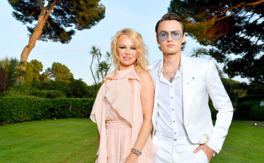 Pamela Anderson and Brandon Thomas Lee posing in a garden at the Cannes Gala in 2019 