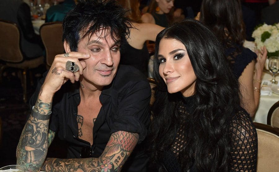 Tommy Lee and Brittany Furlan sitting at a table at a dinner event 