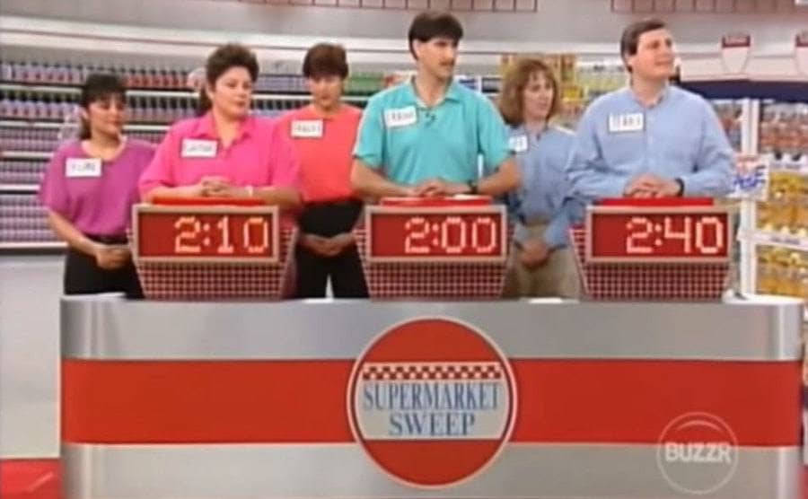Three groups of contestants coupled up with their hands on the buzzer. 