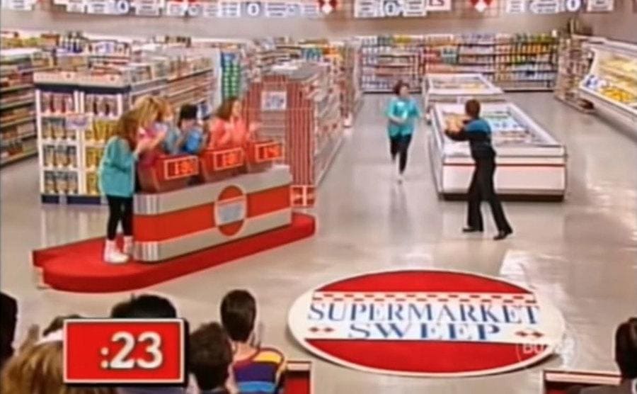 A contestant running next to the freezer section of the supermarket with ’23’ seconds left on the clock 