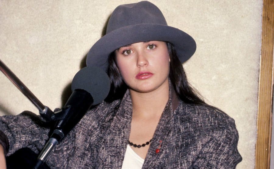 Demi Moore sitting in a chair with a microphone next to her face 