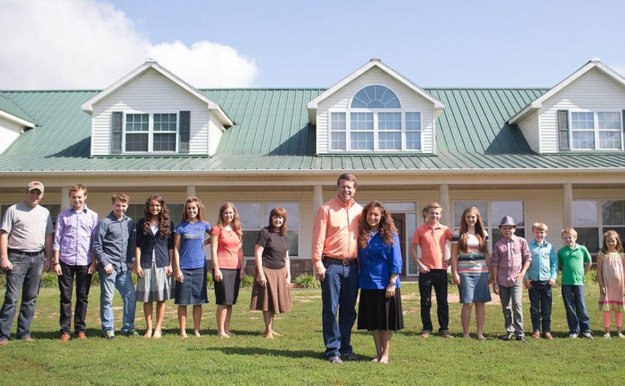 Family Portrait of the Duggar family standing outside and arranged by height. 