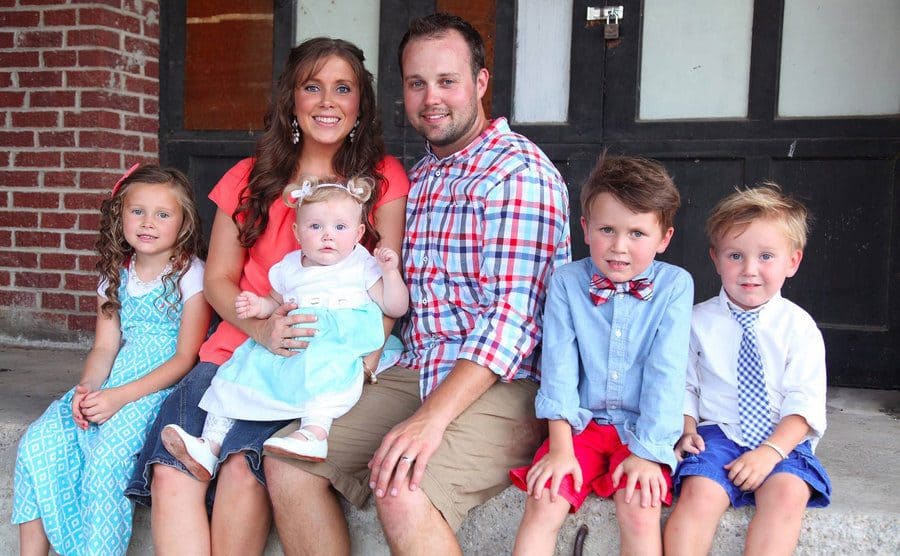 Josh Duggar and his family sitting on the front porch.