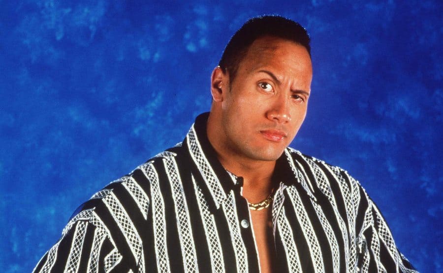 Dwayne Johnson posing for a photo on a blue background 