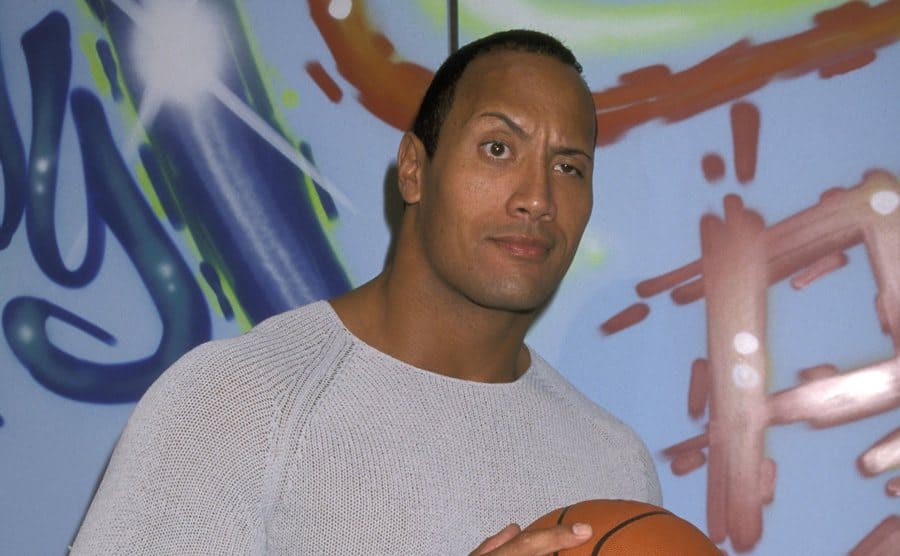 Dwayne Johnson holding a basketball on the red carpet 