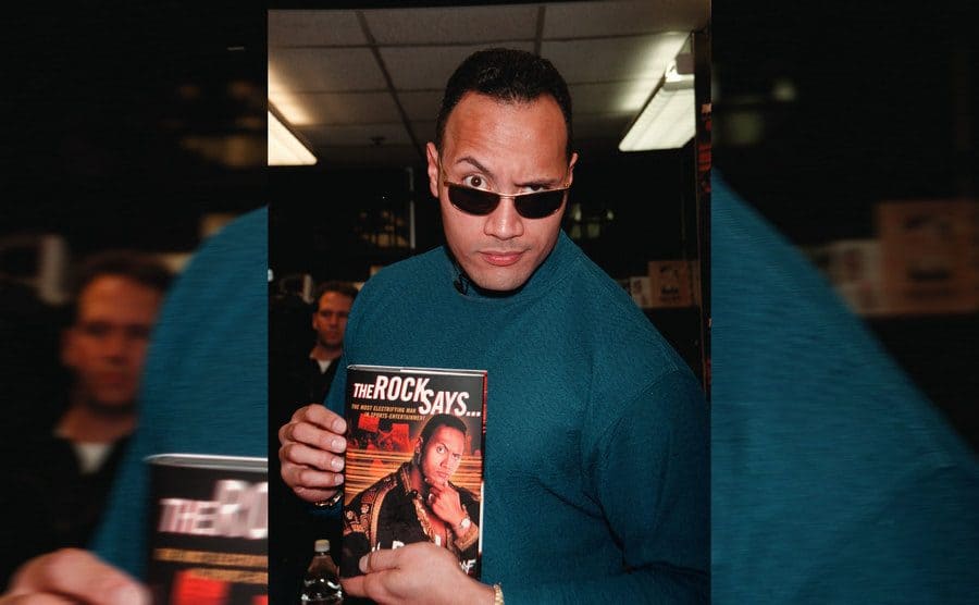 Dwayne Johnson holding up his book, which reads ‘The Rock Says’ 