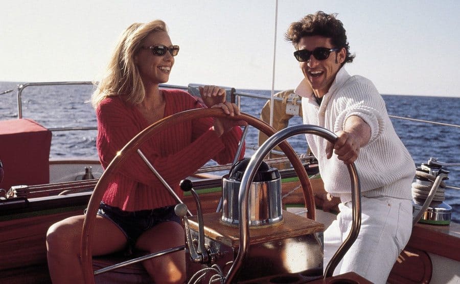 Olivia d’Abo and Patrick Dempsey behind the wheel of a yacht in a scene from Bank Robber
