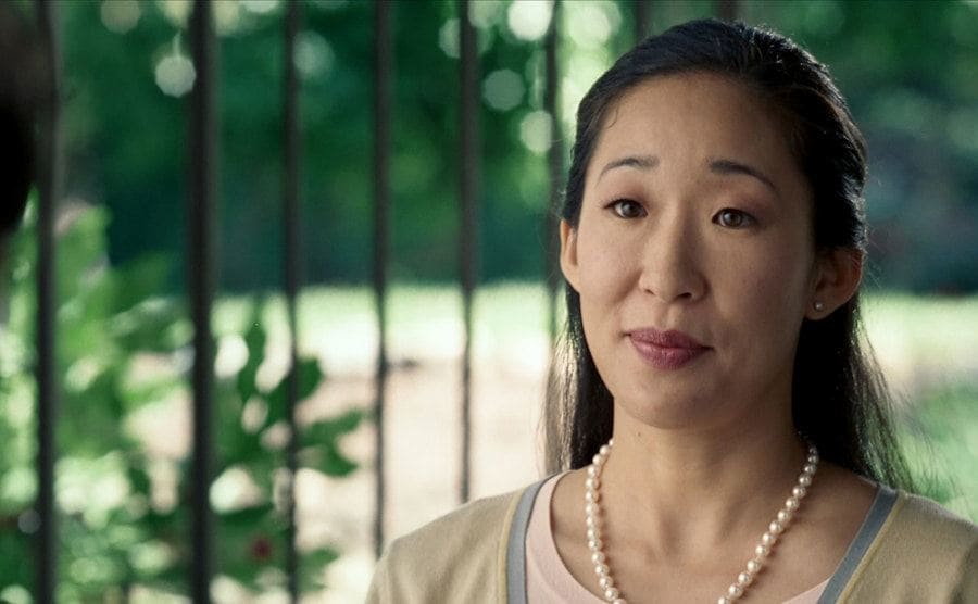 Sandra Oh dressed up in pearls at the front door of a persons home in Hard Candy 
