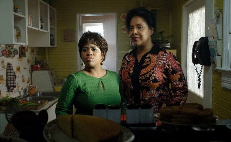 Chandra Wilson and Phylicia Rashad standing in a mustard yellow kitchen in a scene from Frankie and Alice 