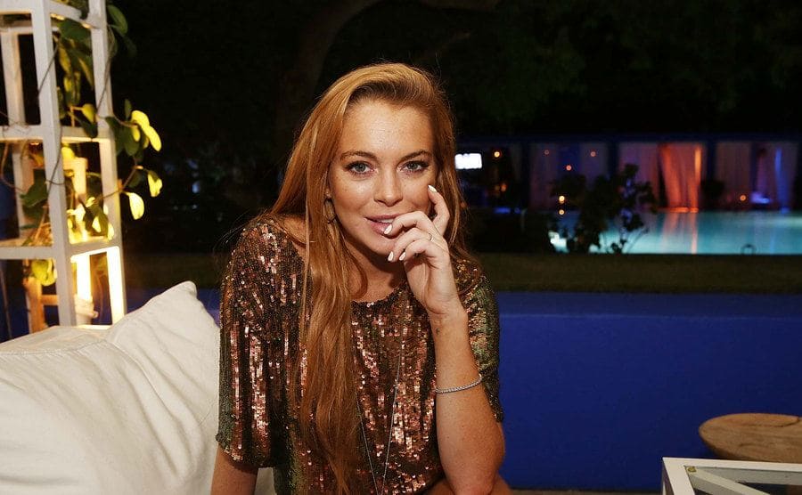 Lindsay Lohan wearing a bronze sequined outfit posing on an outdoor couch by the pool at the Shore Club 