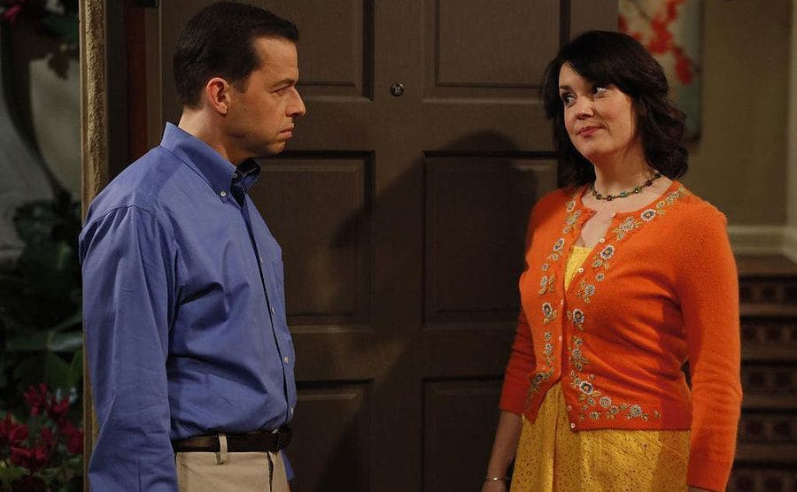 Jon Cryer and Melanie Lynskey standing in a doorway talking in a scene from Two and a Half Men 