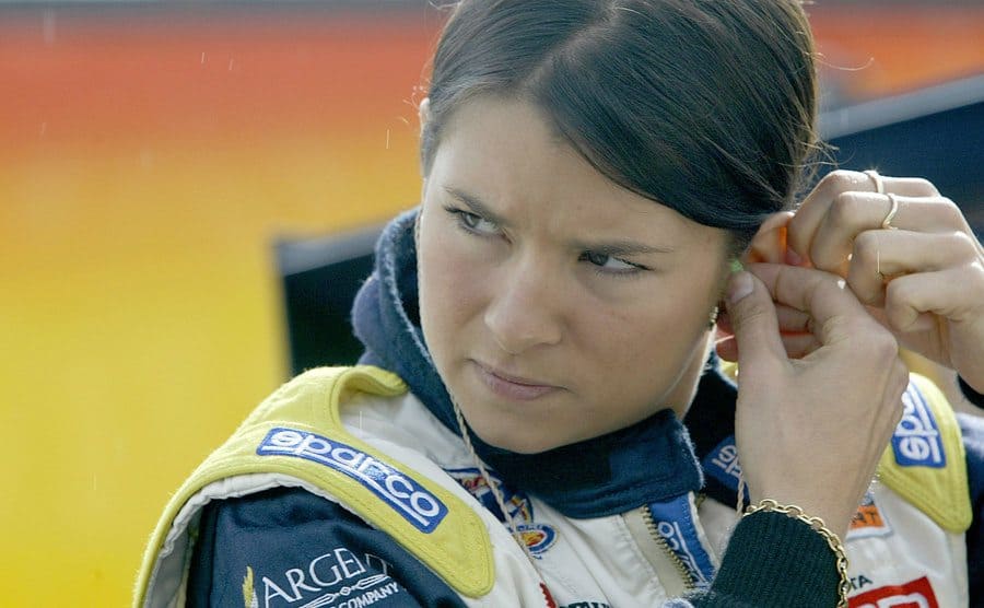 Danica Patrick adjusting her earpiece in racecar gear 
