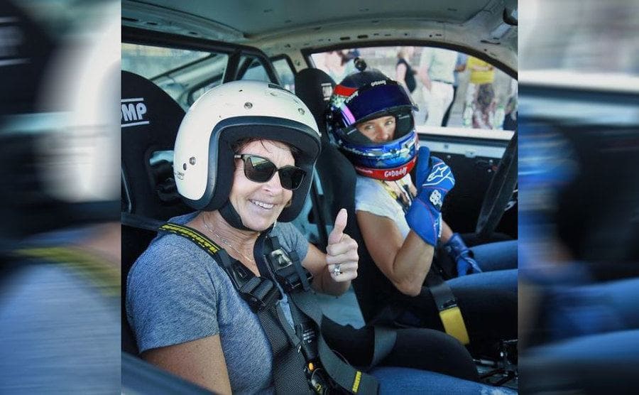Danica and her mother holding their thumbs up for a photograph from inside of a racecar 