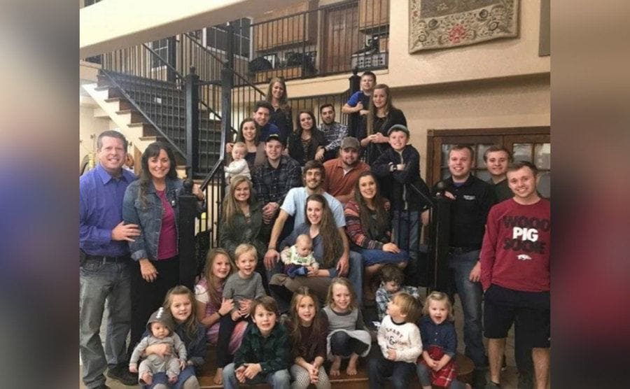 The entire Duggar family is sitting on their staircase at home. 